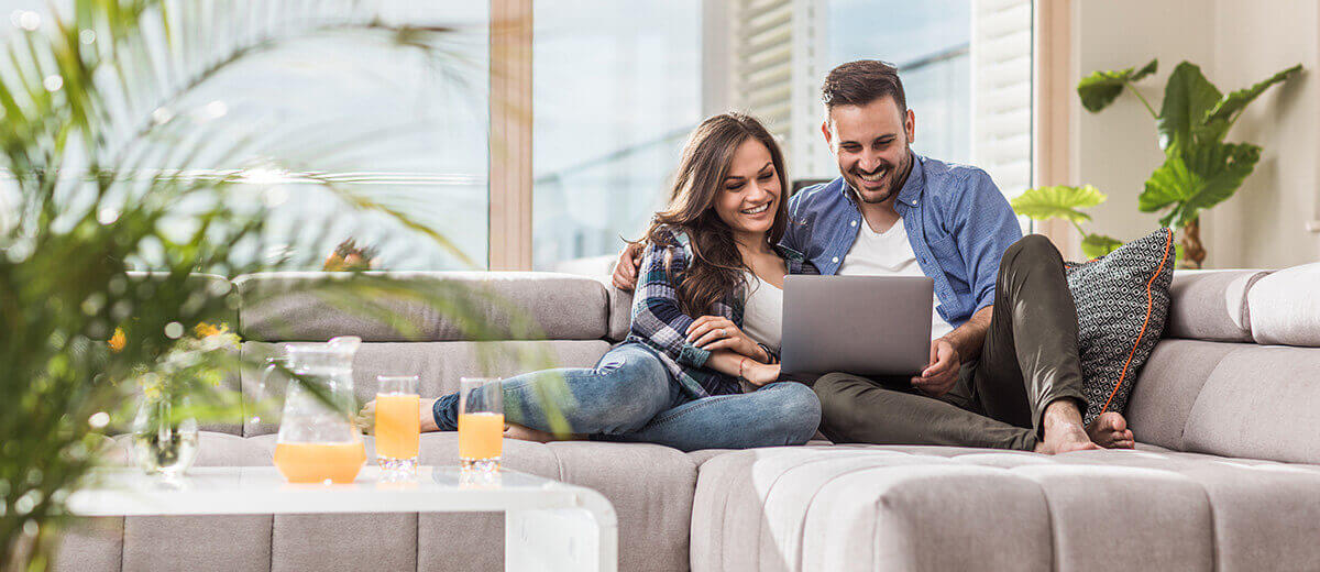 Heizungsmiete - Zwei Personen mit Laptop sitzen auf einem grauen Sofa